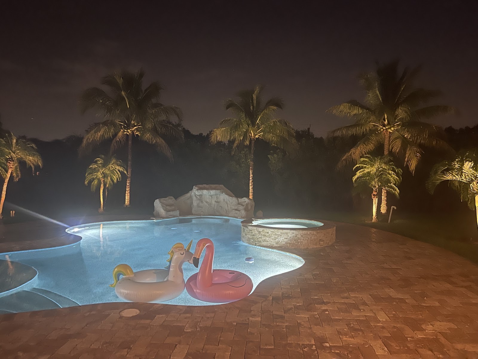 A vacation rental pool at night with lighting, ready for guests