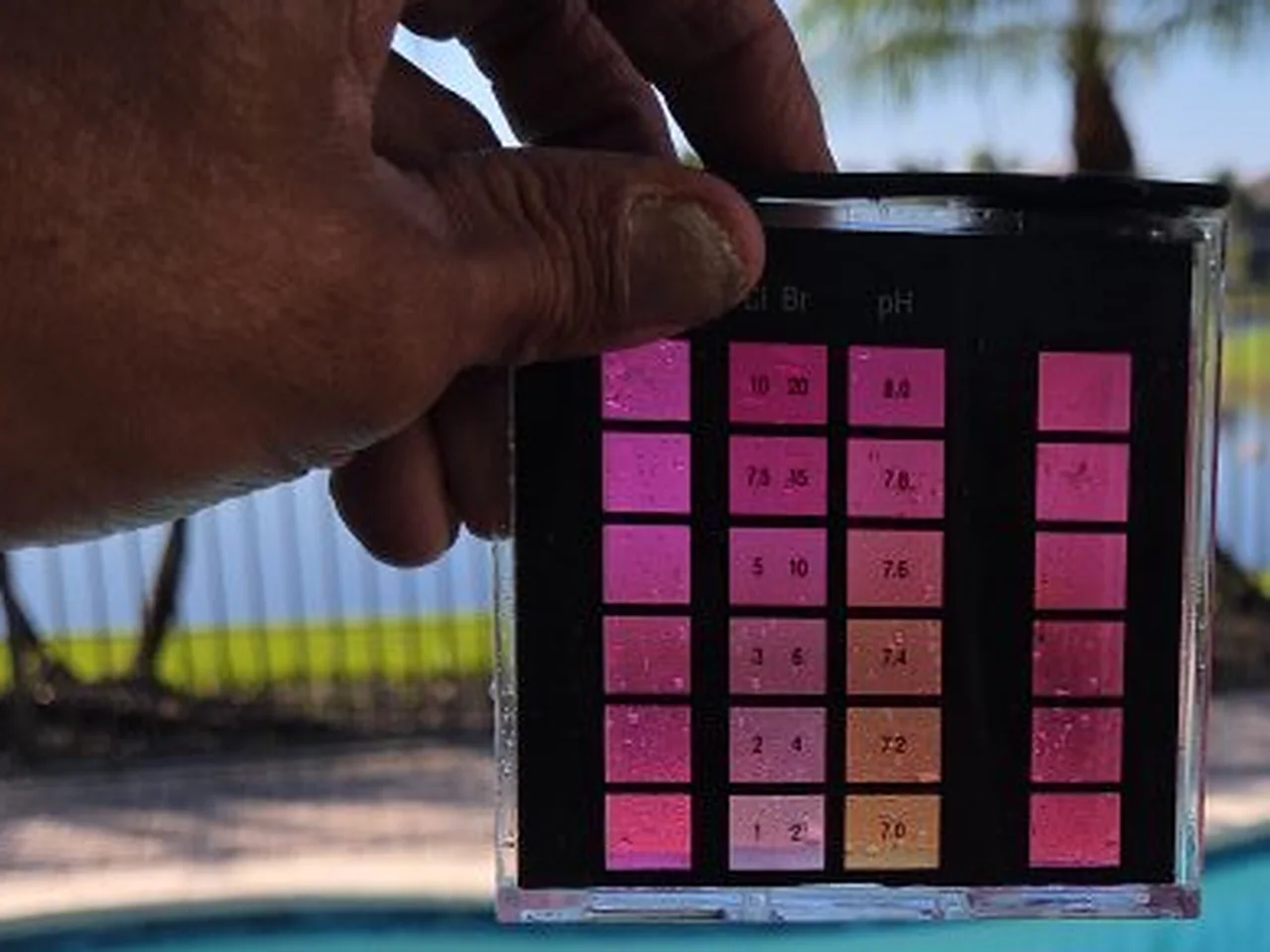 A technician holding a water test kit up to read the chlorine and pH colors